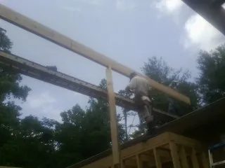 Carpenter setting a ridge beam over a new addition frame — Ice Dam Removal by Roofing Brothers in Russellville