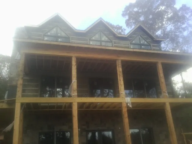 Dormers and porch framing on a large log home under construction — Roof Coating work by our crew in Russellville