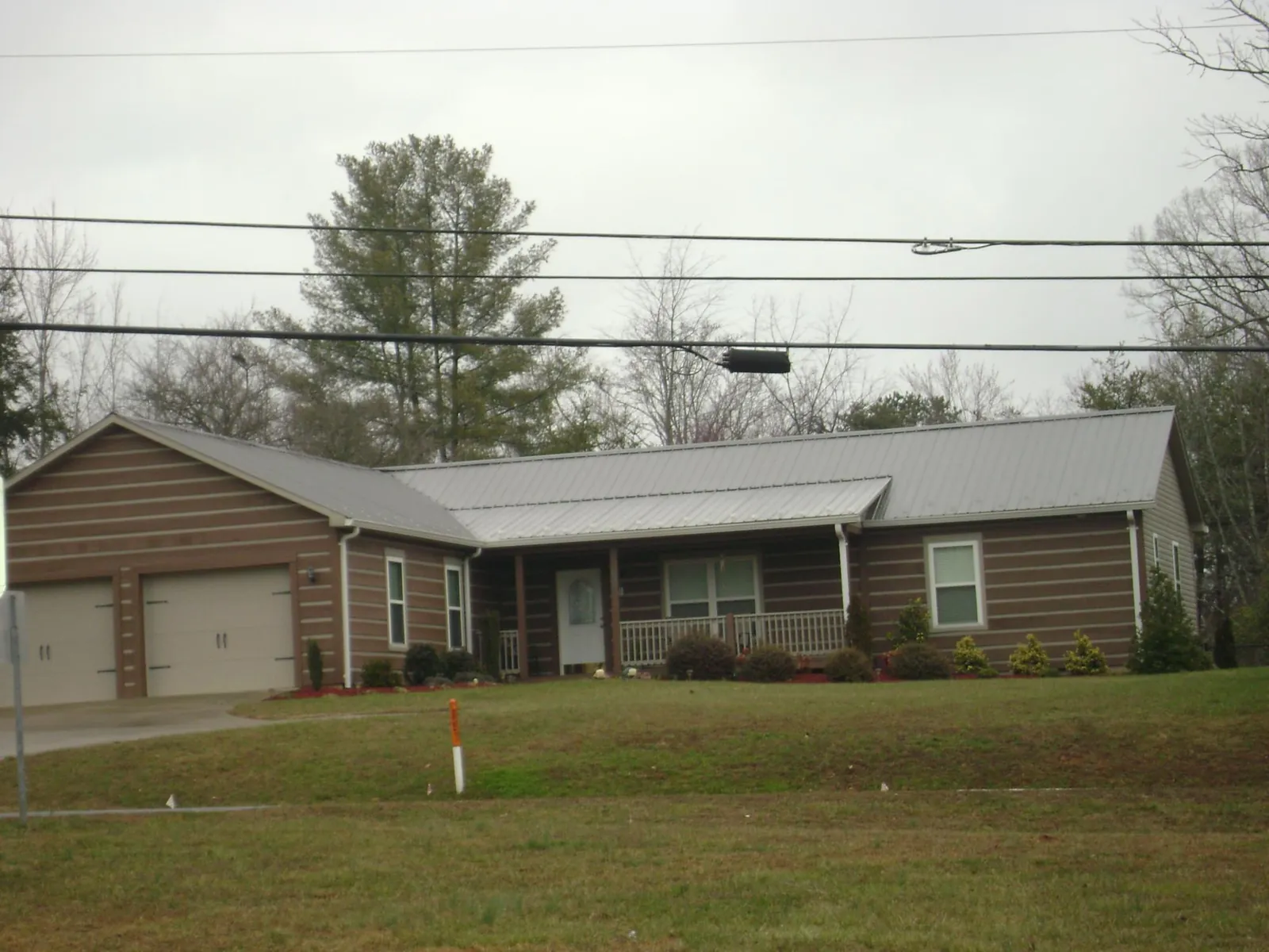 Gray metal roof on a log sided ranch home with a front porch in Russellville